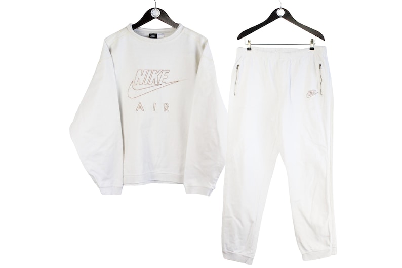 May include: White Nike Air tracksuit with a crew neck sweatshirt and sweatpants. The sweatshirt has a large Nike Air logo with a swoosh on the front.