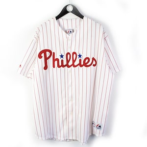 May include: White baseball jersey with red and blue stripes and the word "Phillies" in red with two blue stars above the "i".