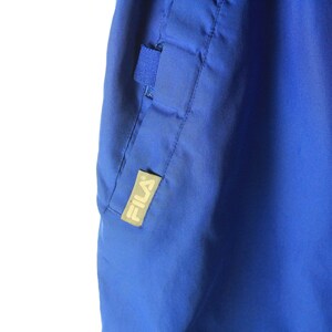 May include: Blue athletic pants with a Fila logo on the side seam.