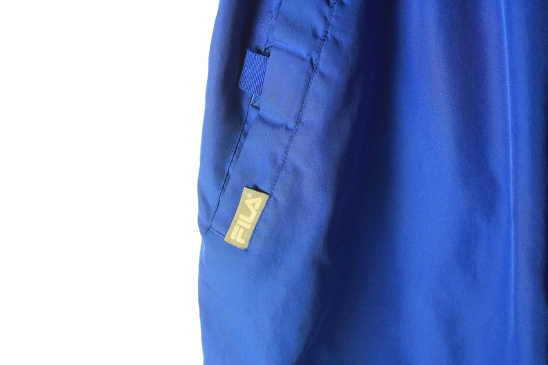 May include: Blue athletic pants with a Fila logo on the side seam.