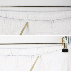 May include: Close-up of the white elastic waistband of a pair of pants. A wooden dowel is used to show the elasticity of the waistband.