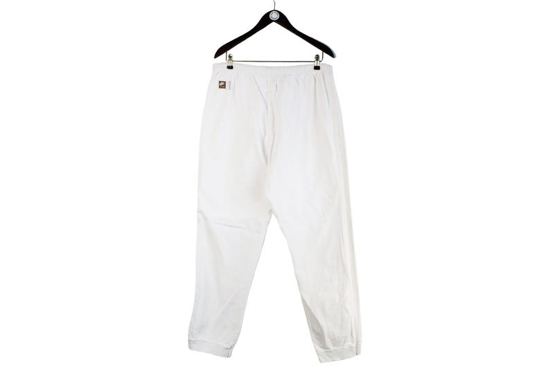 May include: White sweatpants with a drawstring waist and a cuffed hem.