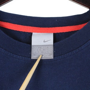 May include: A navy blue t-shirt with a white tag that reads "Size L Height 183 GB 42/44 F 52/54 I 52/54 Made in Turkey Fabrique en Turquie".