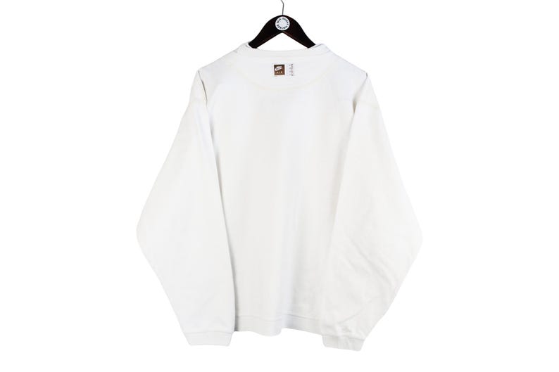 May include: White long-sleeve sweatshirt with a small brown Nike logo on the back.