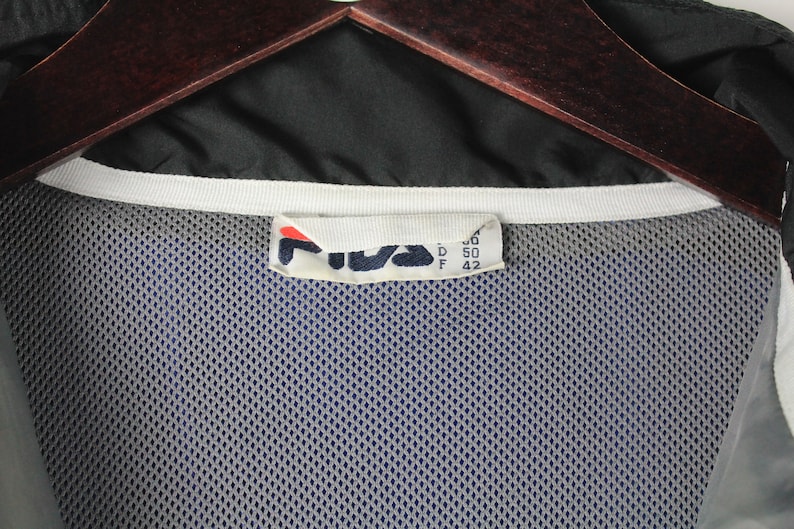 May include: A black Fila windbreaker jacket with a white zipper and a mesh lining. The size tag reads "M, D 50, F 42".