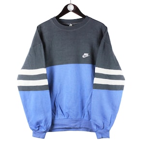 May include: A blue and gray sweatshirt with white stripes on the sleeves. The sweatshirt has a Nike logo on the front.