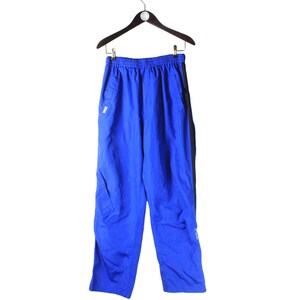 May include: Blue athletic pants with black side panels. The pants have a drawstring waistband and a zippered pocket on the right leg.