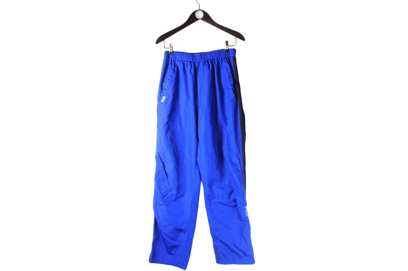 May include: Blue athletic pants with black side panels. The pants have a drawstring waistband and a zippered pocket on the right leg.