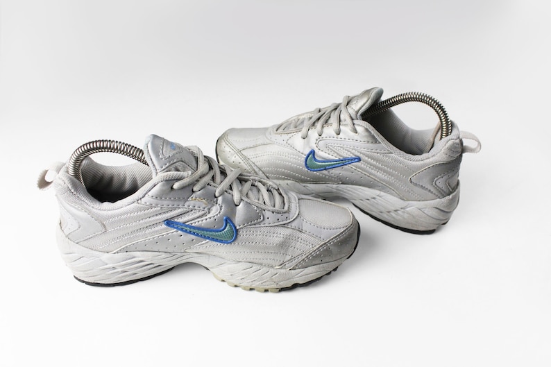 May include: A pair of gray athletic shoes with blue and green accents. The shoes have a white sole and a lace-up closure.