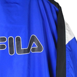 May include: Blue, black, and white windbreaker jacket with the word "FILA" in black and white on the back.