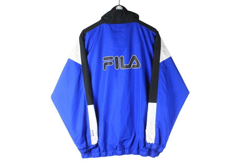 May include: A blue, black, and white Fila windbreaker jacket with a white Fila logo on the back.