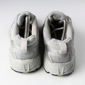 May include: A pair of white athletic shoes with blue accents. The shoes have a mesh and leather upper and a thick rubber sole.