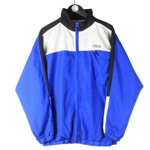 May include: A blue, white, and black Fila windbreaker jacket with a zipper closure. The jacket has a white panel across the chest with the Fila logo in black.