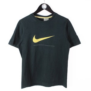 Peut inclure: Un t-shirt noir &agrave; manches courtes avec un logo Nike swoosh jaune.