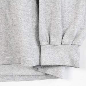 May include: Close-up of the gray fabric cuff of a long-sleeve shirt. The cuff is folded over and stitched.