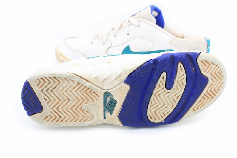 May include: White leather sneakers with blue and teal accents. The sneakers have a white rubber sole with a blue and white pattern.