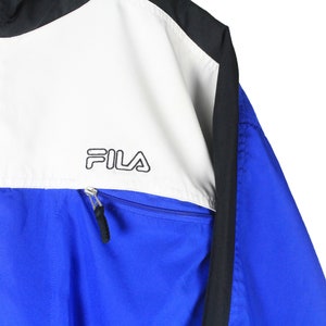 May include: A blue, white, and black windbreaker jacket with a zipper closure and the word "FILA" printed on the white panel.
