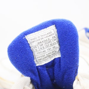 May include: A white shoe with a blue fabric lining. The shoe size is US 5, UK 4.5, EUR 37.5, CM 23.5. The label also states "Made in Thailand" and "Patent 4,562,651 and Foreign Pat."