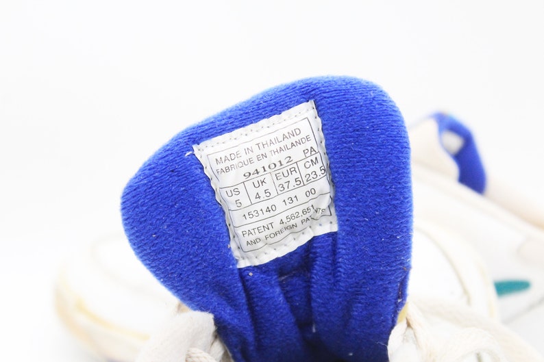 May include: A white shoe with a blue fabric lining. The shoe size is US 5, UK 4.5, EUR 37.5, CM 23.5. The label also states "Made in Thailand" and "Patent 4,562,651 and Foreign Pat."