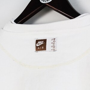 May include: White cotton sweatshirt with a brown Nike Air logo and the text "100% Cotton" on the bottom.