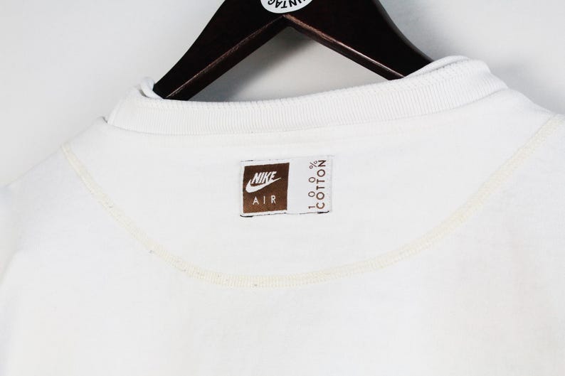 May include: White cotton sweatshirt with a brown Nike Air logo and the text "100% Cotton" on the bottom.