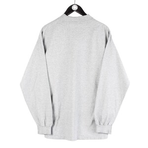 May include: A gray long-sleeve shirt with a mock neck.