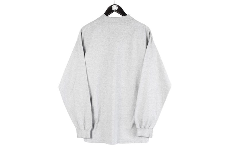 May include: A gray long-sleeve shirt with a mock neck.