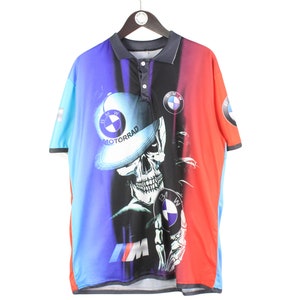 May include: A blue, black, and red short-sleeved polo shirt with a skull wearing a BMW Motorrad hat and holding a BMW logo. The shirt has a colorful, abstract design.