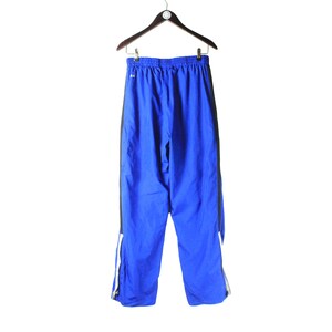 May include: Blue athletic pants with black and white trim. The pants have a drawstring waist and a relaxed fit.