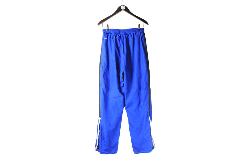 May include: Blue athletic pants with black and white trim. The pants have a drawstring waist and a relaxed fit.