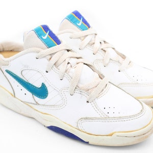 May include: White leather sneakers with blue and yellow accents. The sneakers have a white sole with a blue trim.