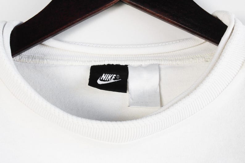 May include: White t-shirt with a black Nike logo on the front.