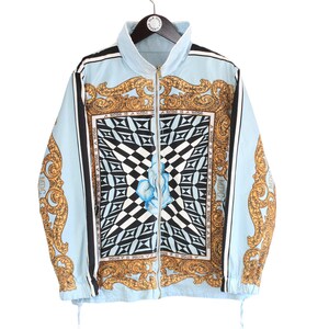 May include: A light blue jacket with a gold and black patterned design. The pattern features a square with a chequered design and a blue flower in the centre. The jacket has a zip closure and a drawstring at the bottom.