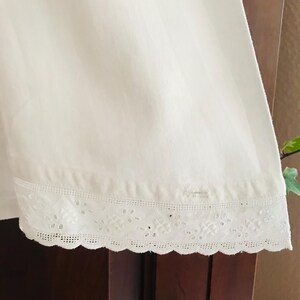 May include: White cotton fabric with a scalloped edge and delicate eyelet lace trim.