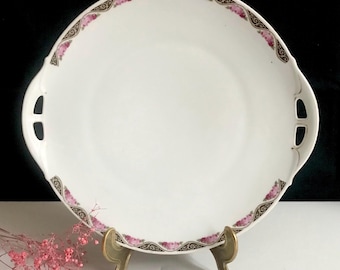May include: A white porcelain serving platter with two handles. The platter features a decorative border with pink roses and gold accents.