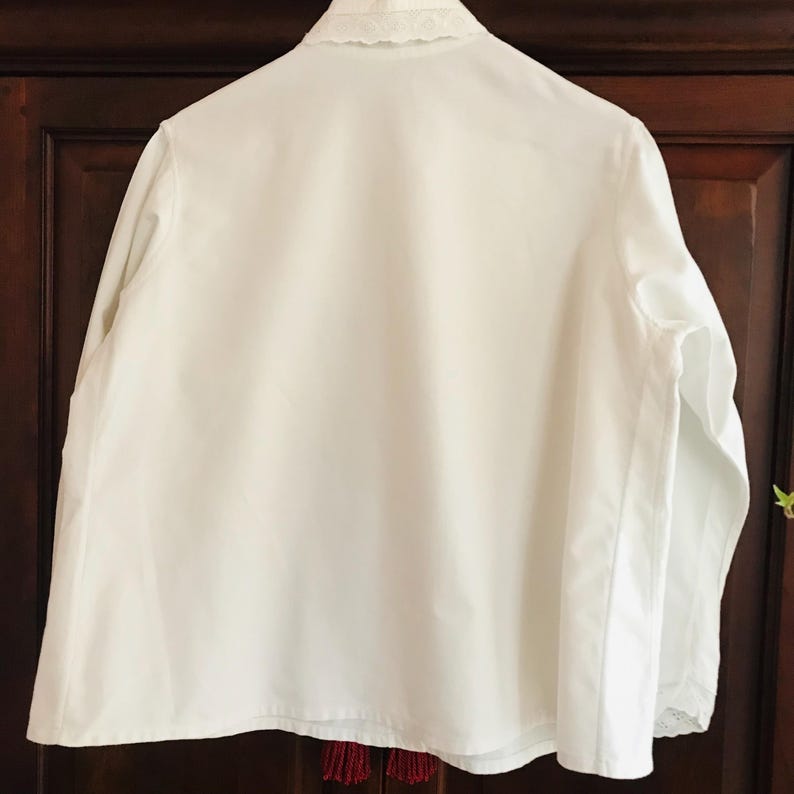 May include: A white long-sleeved shirt with a lace collar. The shirt is made of a lightweight fabric and has a relaxed fit.