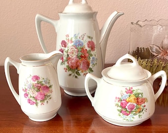 Art Nouveau coffee pot, sugar bowl, and creamer with typical period decorations. Antique porcelain centerpiece.