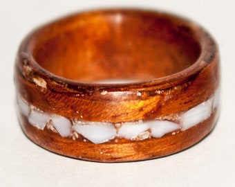 Anillo de madera con incrustaciones de concha blanca.