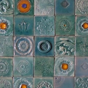 Può includere: Una collezione di 36 piccole piastrelle quadrate in ceramica blu e verde con vari motivi decorativi. Ogni piastrella presenta un design diverso, tra cui motivi floreali, forme geometriche e motivi astratti.