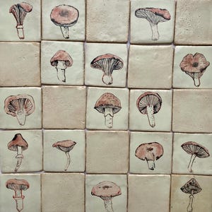 Peut inclure: Un ensemble de carreaux carrés, chacun orné d'une illustration de champignon dessinée à la main. Les champignons sont représentés dans des tons bruns et beiges, avec des formes variées. Les carreaux ont un fond blanc cassé neutre.