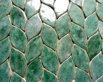 May include: Green ceramic tile mosaic with a leaf pattern. The tiles are arranged in a staggered pattern, creating a wave-like effect.