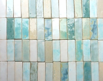 May include: A collection of rectangular ceramic tiles in various shades of blue and white. The tiles have a rustic, handmade look and are arranged in a grid pattern.