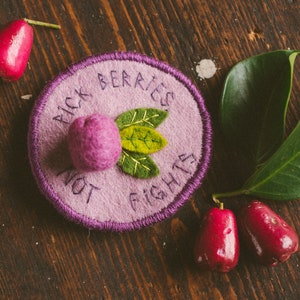Felt handmade badge with a lilli pilli fruit and some leaves, the text reads: Pick berries, not fights