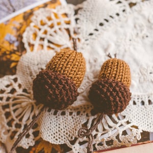 Two bookmark acorn charms as shown against white retro doily