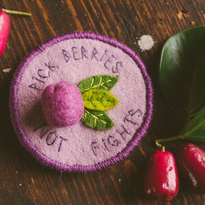 Felt handmade badge with a lilli pilli fruit and some leaves, the text reads: Pick berries, not fights