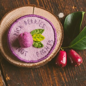 Felt handmade badge with a lilli pilli fruit and some leaves, the text reads: Pick berries, not fights