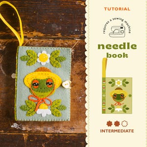 May include: A handmade needle book featuring a frog design. The cover is pale green with a frog wearing a yellow hat and an orange bow. The book has a yellow ribbon loop and a button closure. The text "needle book" is visible.
