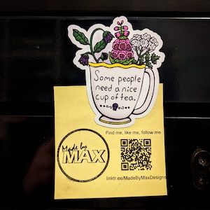 May include: A white teacup with a yellow rim and floral design. The teacup has the text "Some people need a nice cup of tea." printed on it. The teacup is on a yellow background with a black and white stamp that says "Made by MAX" and a QR code.