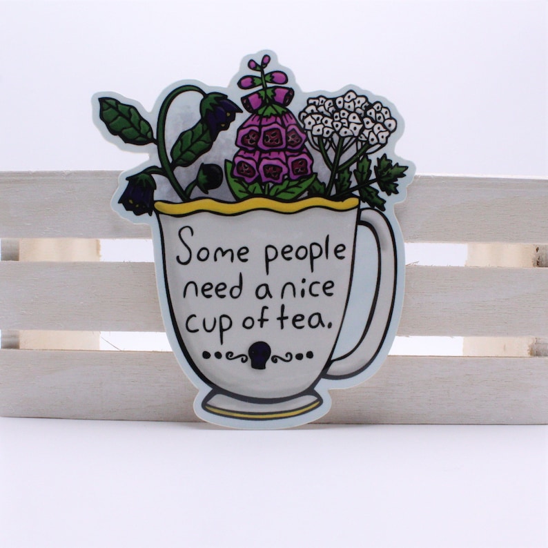 May include: A white teacup with a yellow rim and a handle, filled with purple and white flowers. The text "Some people need a nice cup of tea." is written on the cup.
