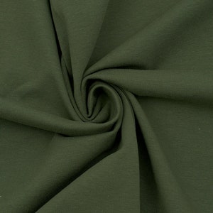 Könnte beinhalten: Nahaufnahme eines dunkelgrünen Rippstoffs. Der Stoff ist gefaltet und drapiert und zeigt seine Textur und seinen Fall.